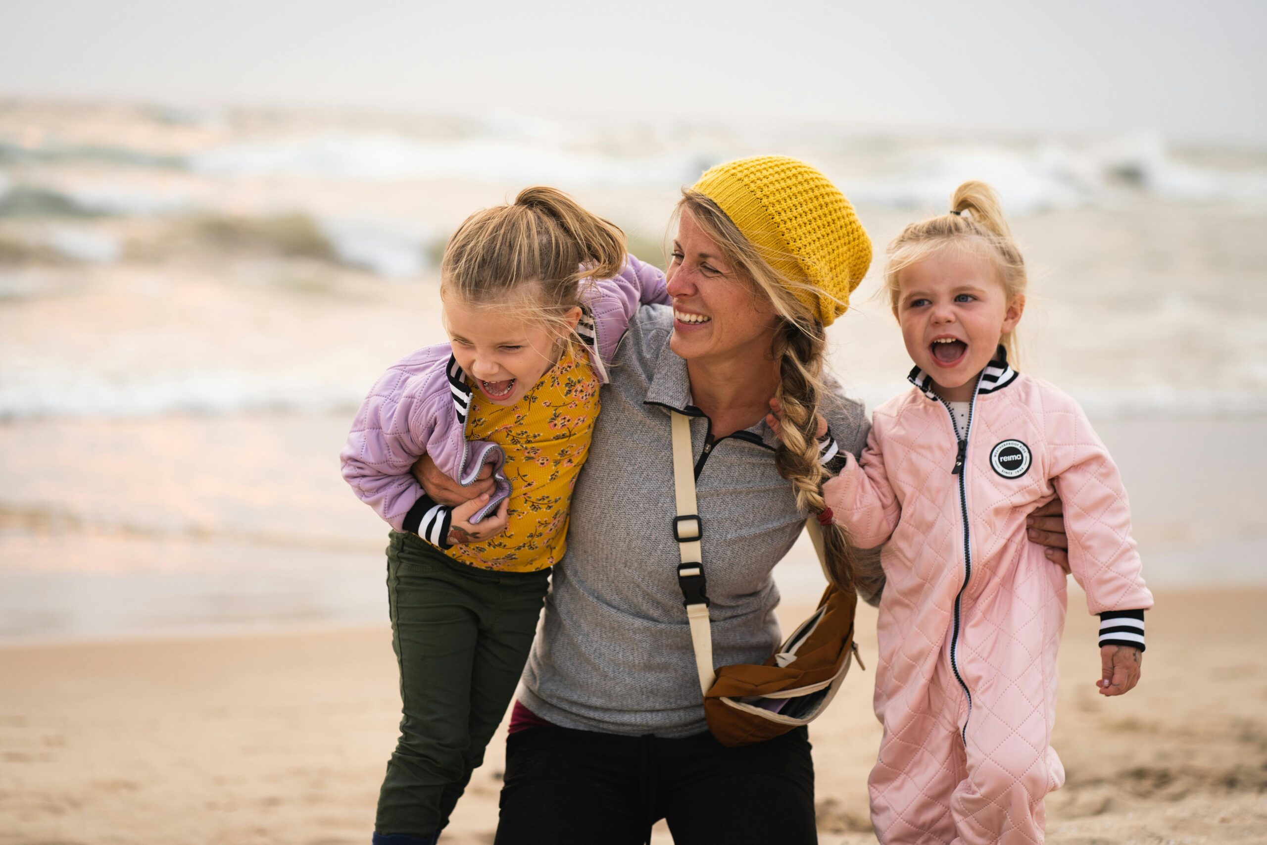 Mother and daughters enjoying a playful day at the beach, embracing laughter and love.